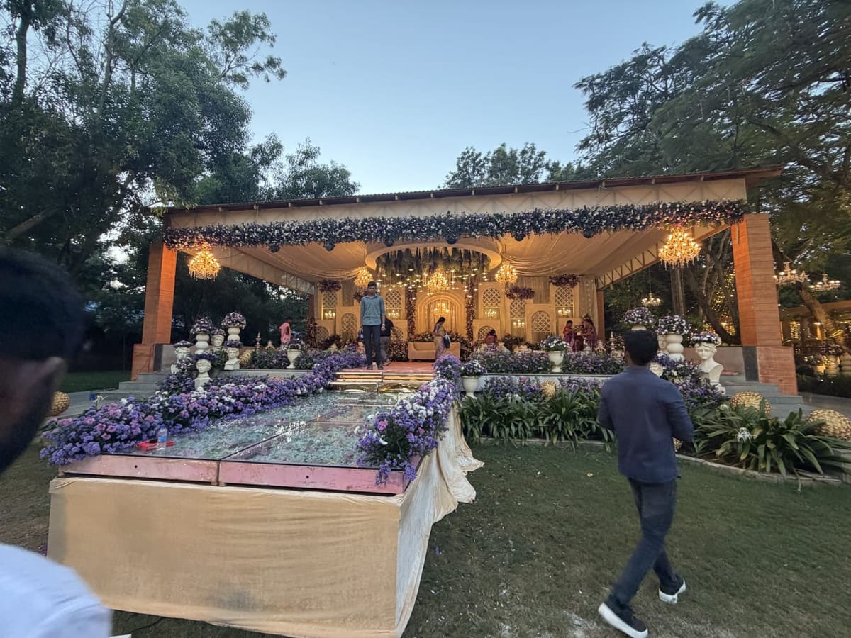 The wedding mandap dressed with flowers and a chandelier on the lawn